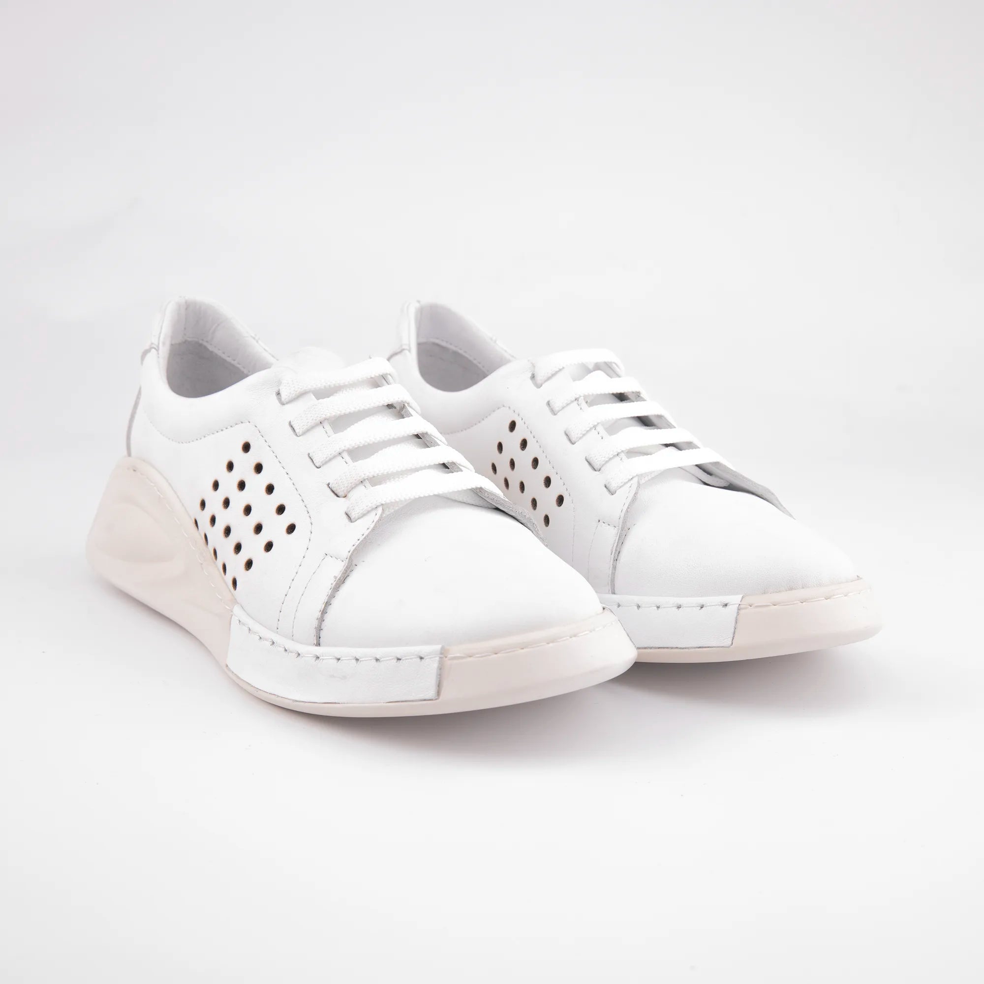 A pair of MrCalvano Laguna Beach white leather comfort shoes with perforated sides and a subtle wedge heel, angled slightly to show the textured sole.