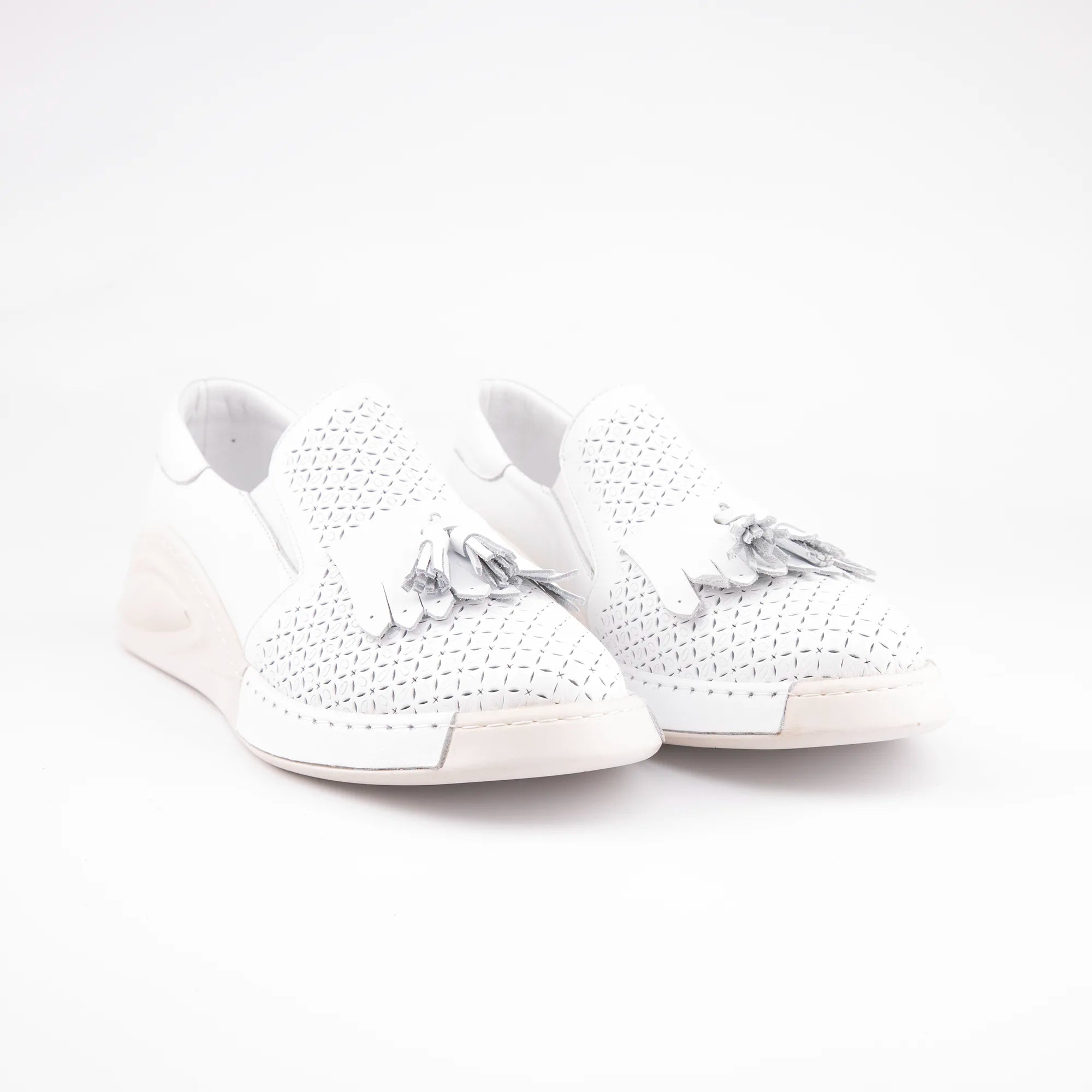 A United State studio shot showcasing the MrCalvano Newport Beach white leather women's slip-on shoes, highlighting the perforated texture and tassel detail.