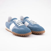 A United State studio shot highlighting the texture and color of the blue leather upper, white detailing, and gum sole of the Pebble Beach women's sneakers, emphasizing material quality.