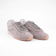 Close-up view of the MrCalvano Pismo Beach grey leather women's sneaker, highlighting the soft texture of the leather, the clean stitching, and the signature light brown rubber sole. Perfect for visual details on material and craftsmanship.
