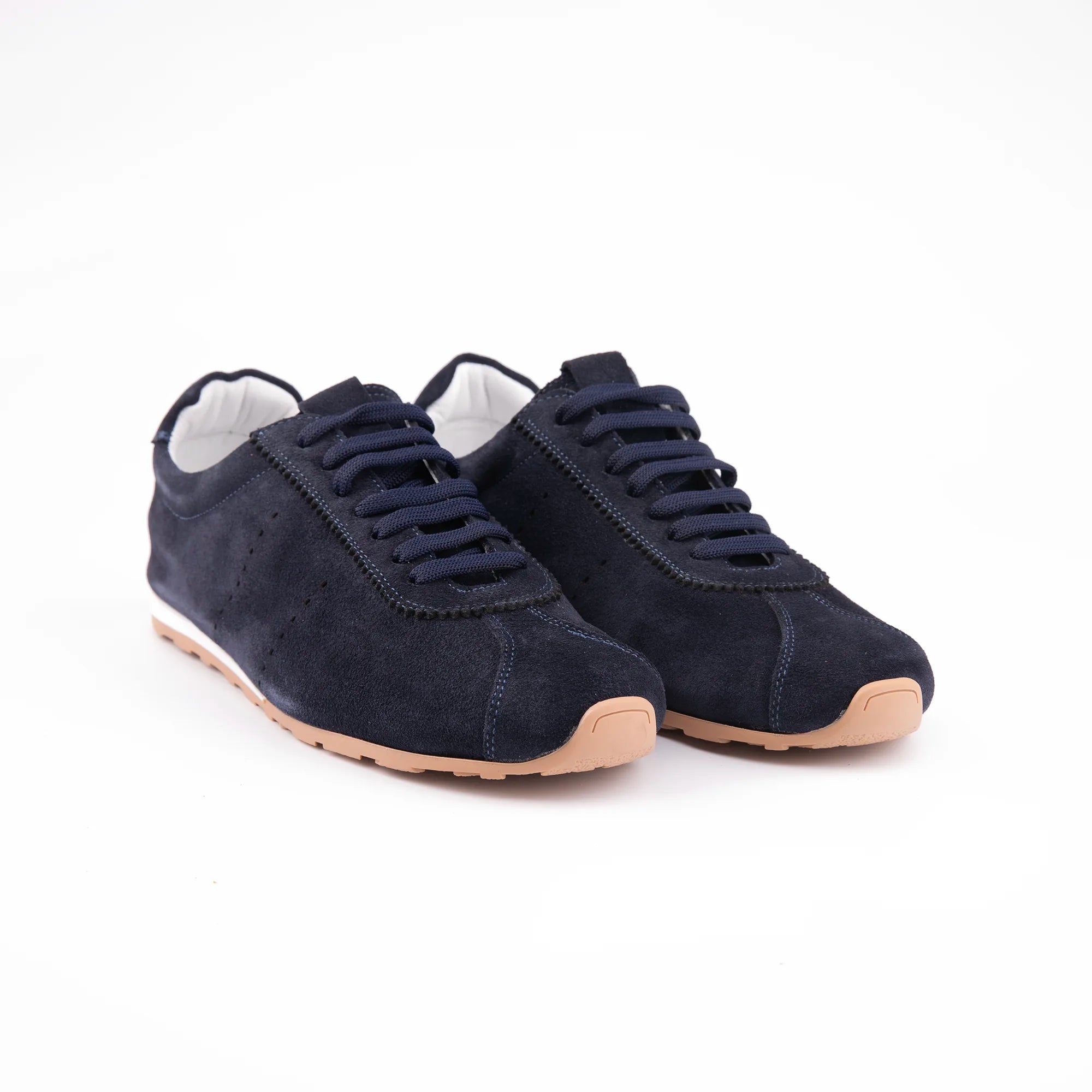 A pair of Pismo Beach navy leather men's sneakers, featuring a supple suede upper, clean white midsole stripe, and a caramel tan gum rubber outsole. The low-profile silhouette and detailed stitching highlight its refined casual style.