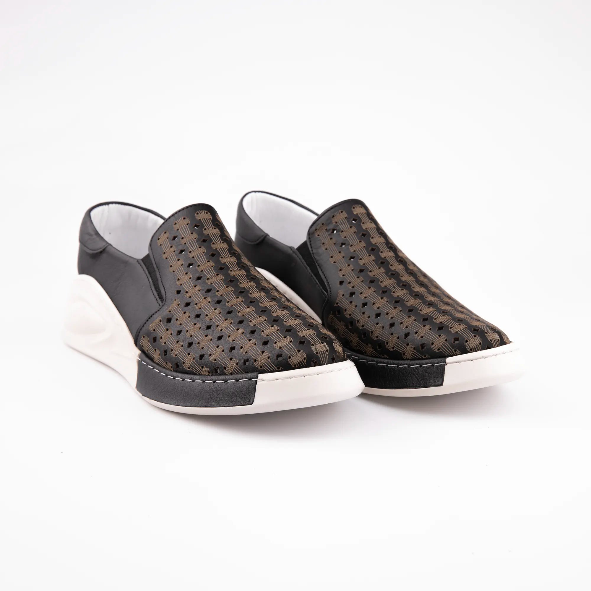 A pair of MrCalvano Solana Black Leather Women's Slip-On Shoes, showcasing the perforated black and bronze leather upper, the distinctive off-white sculpted sole, and the contrasting white stitching at the toe. Shot on a white background, emphasizing the modern design and materials ideal for wear in the United State.