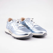 A pair of MrCalvano Venice Beach Ice Box Leather Women's Sneakers, showcasing their distinctive metallic blue upper, intricate lacing system with silver eyelets, and multi-layered sculpted sole, against a clean white background. The image highlights the shoe's contemporary aesthetic and material quality.