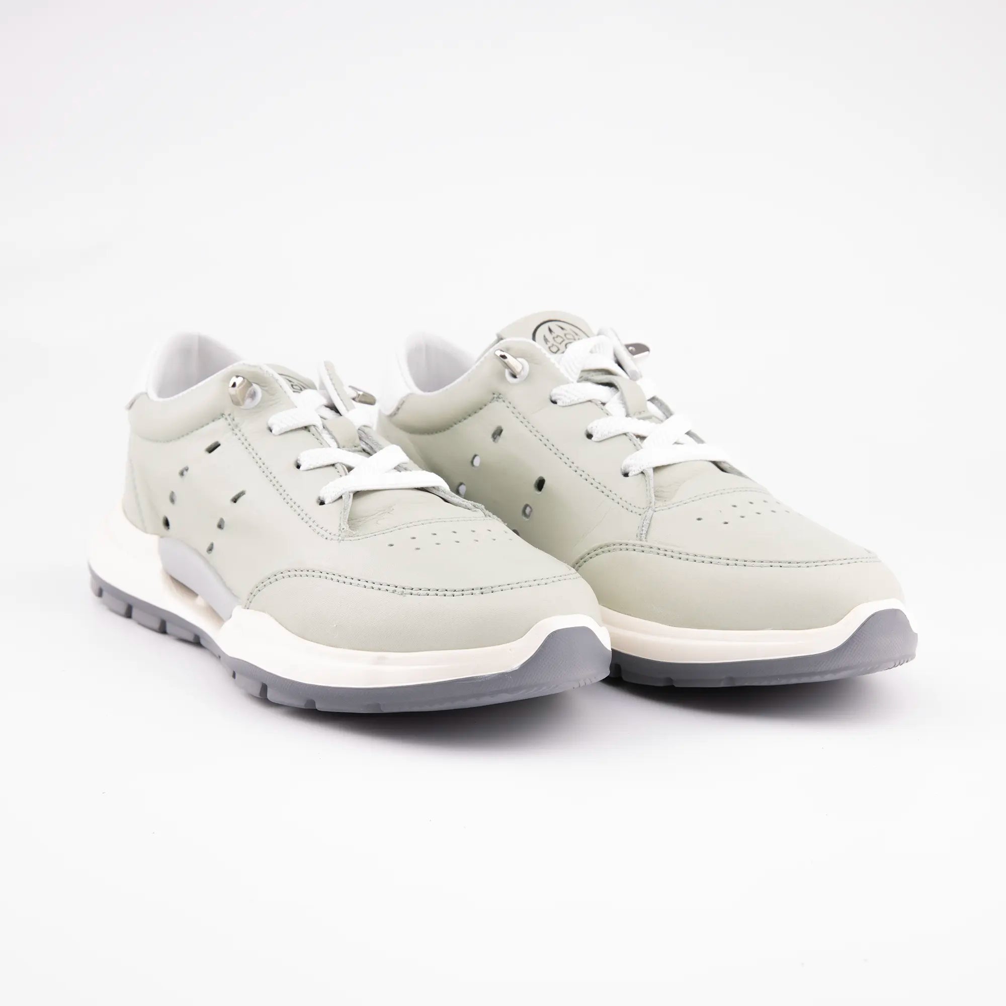 A pair of MrCalvano Venice Beach Mint Leather Women Casual Shoes, photographed at a slight angle on a clean white background, highlighting the pale mint green leather upper, bright white laces, off-white sculpted midsole, and dark grey textured outsole. The perforations on the side panel and the metallic lace eyelets are visible.
