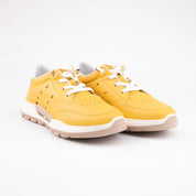 A pair of MrCalvano Venice Beach mustard yellow leather women's sneakers, featuring a sculpted warm ivory midsole and pale taupe outsole, white laces, and gold-tone eyelets, presented on a clean white background.